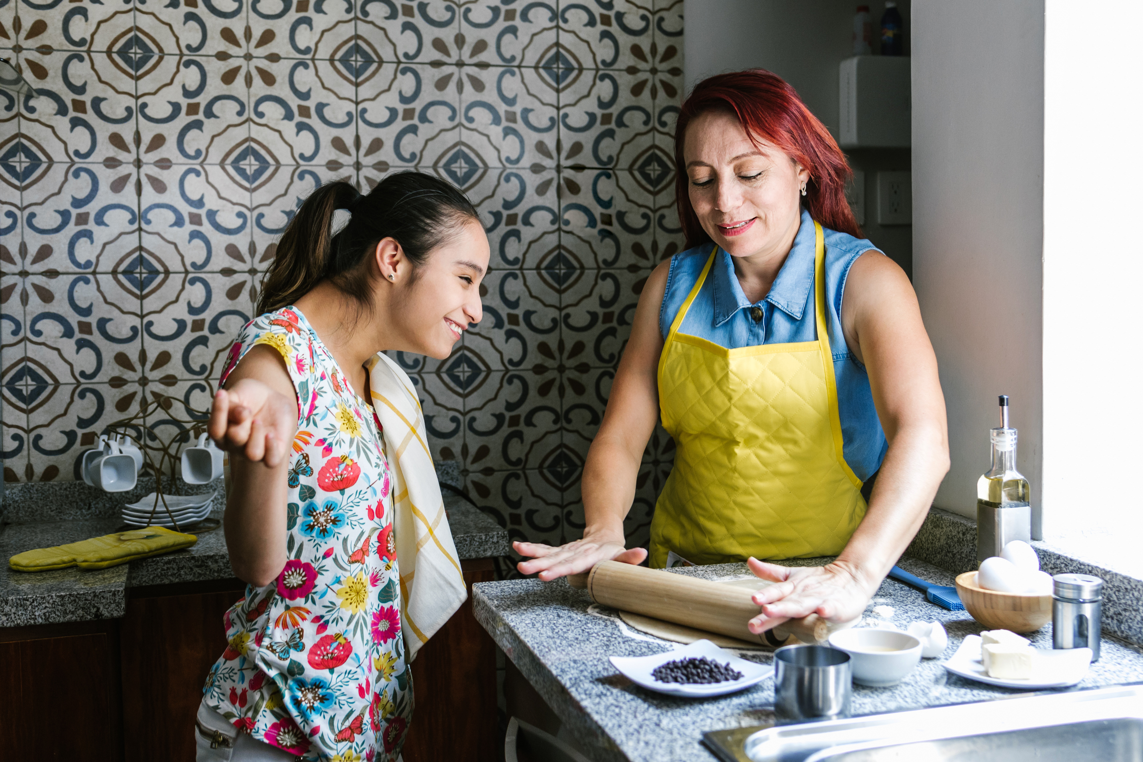 A person with a disability and a support person prepare food together at a kitchen bench.