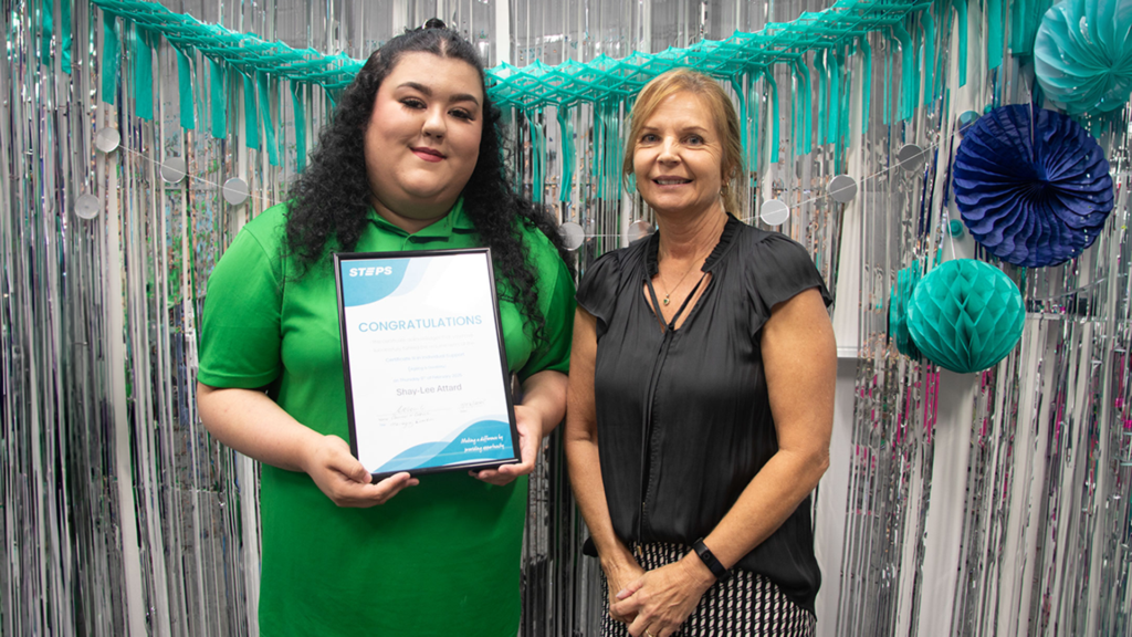 Shay-Lee standing next to a woman in front of a wall decorated with streamers.