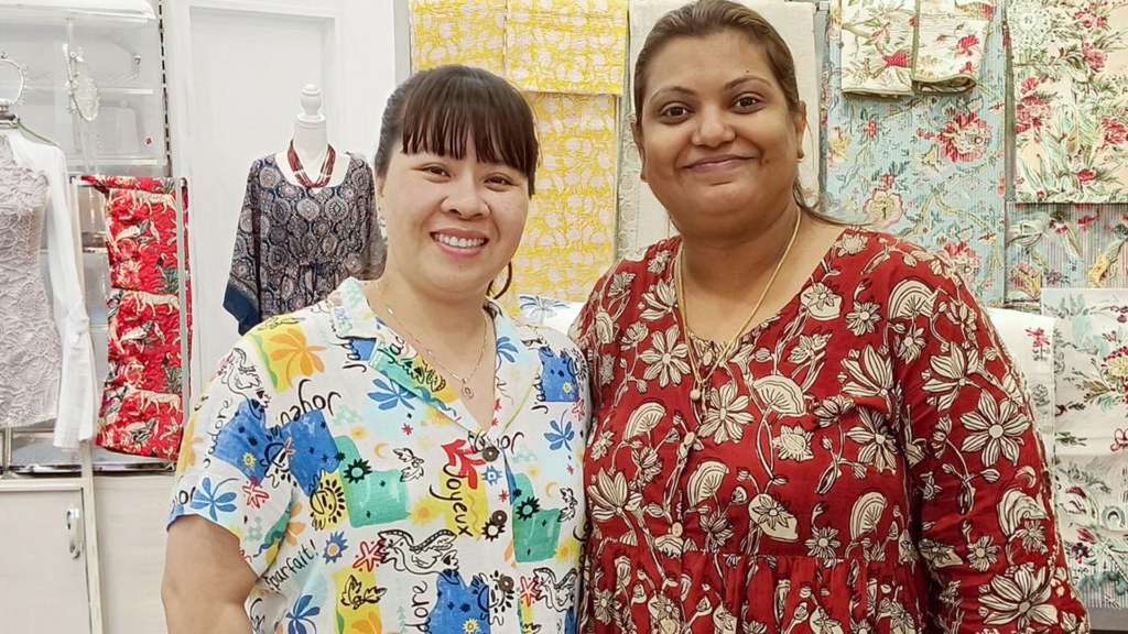 STEPS AMEP Ready for Work Program participants standing in a room with different fabrics and smiling at the camera.