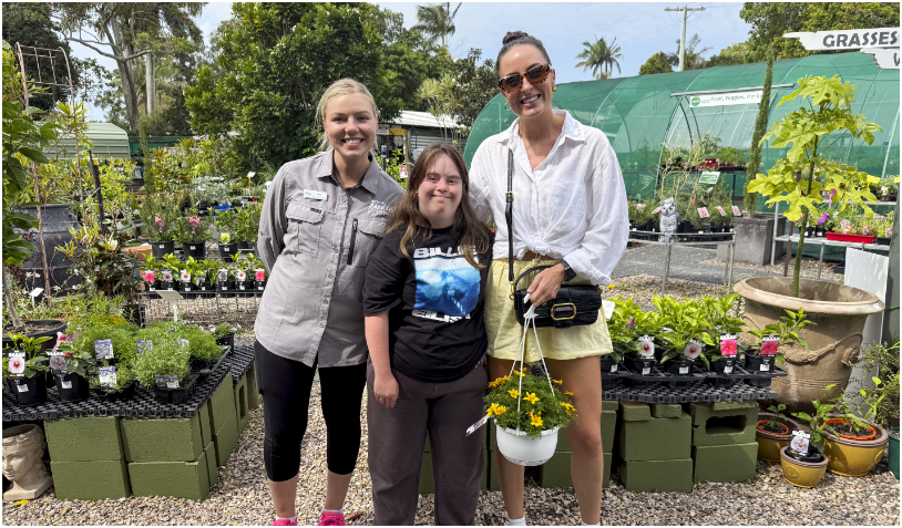 A STEPS Pathways College participant, a STEPS Garden Centre staff member and a customer smiling.