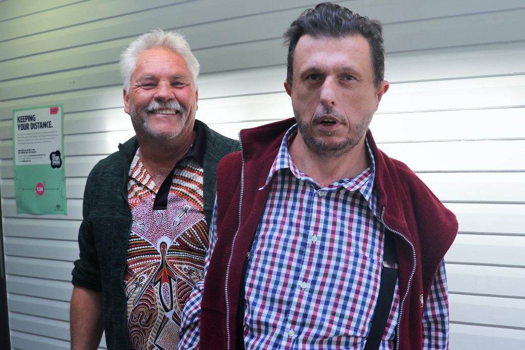 Disability support worker stands next to his client, smiling.