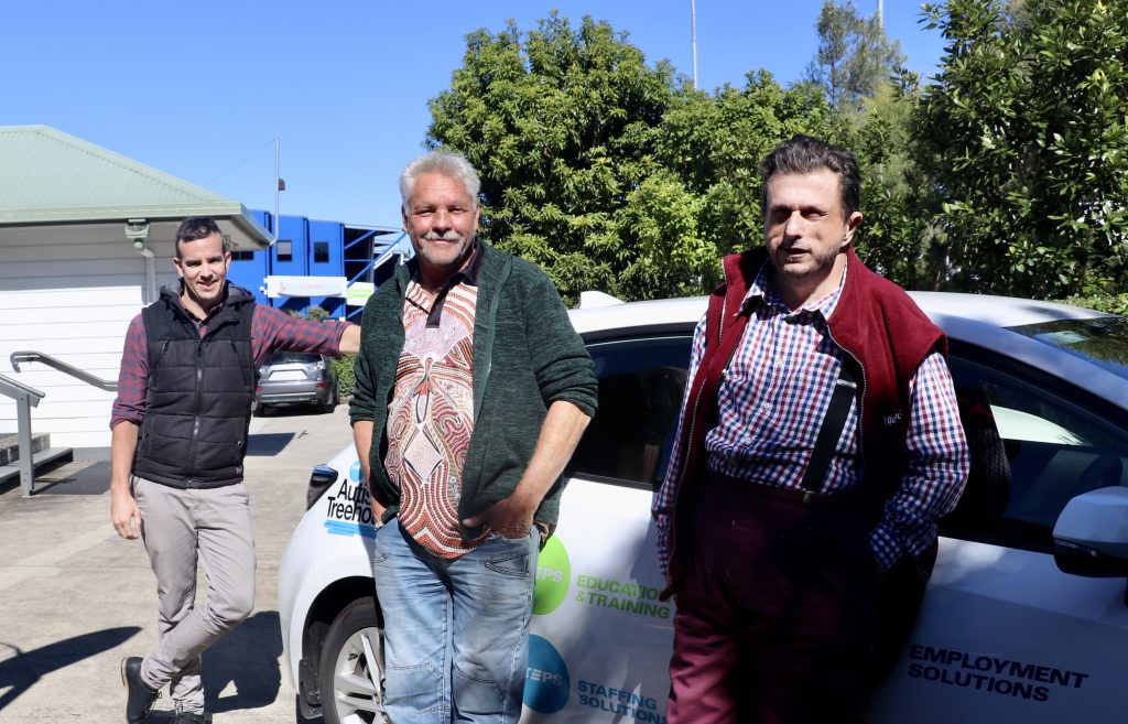 3 men from STEPS stand together outside leaning against car