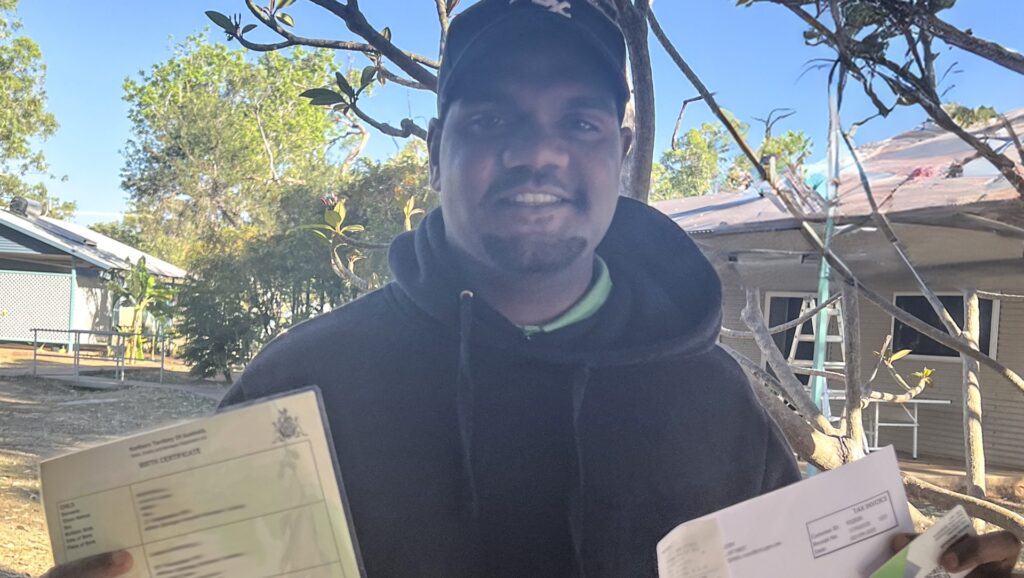 STEPS participant smiling and holding their birth certificate and STEPS ID card.